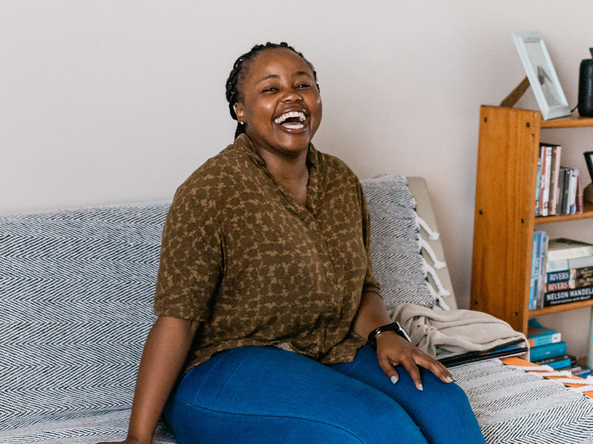 woman seated on couch laughing