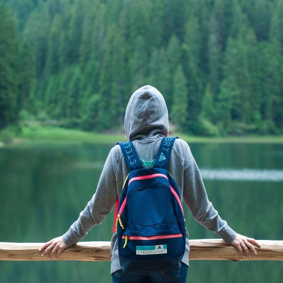person with hiking backpack looking at lake