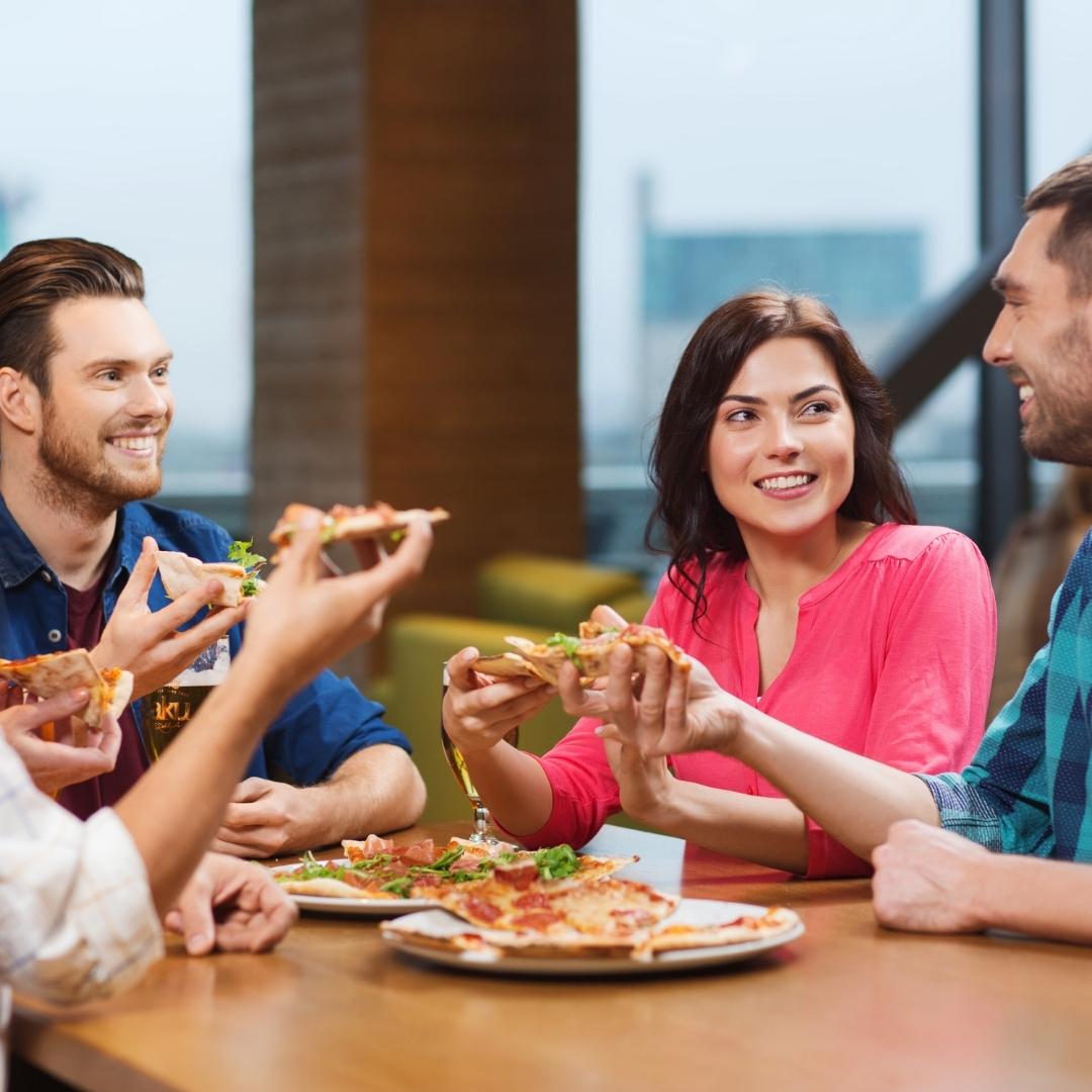 friends eating pizza at restaurant