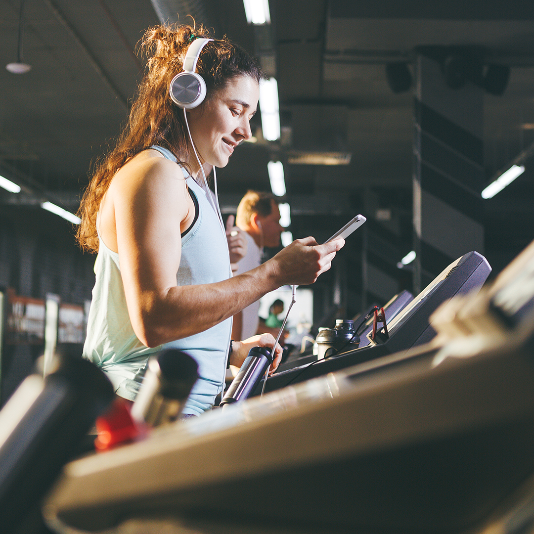 woman happily looking at her phone while working out