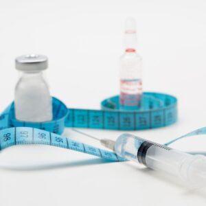 Various weight loss injections with a tape measure wrapped around it. 
