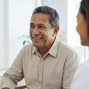 A patient smiles genuinely during a medical consultation in a bright clinic setting.